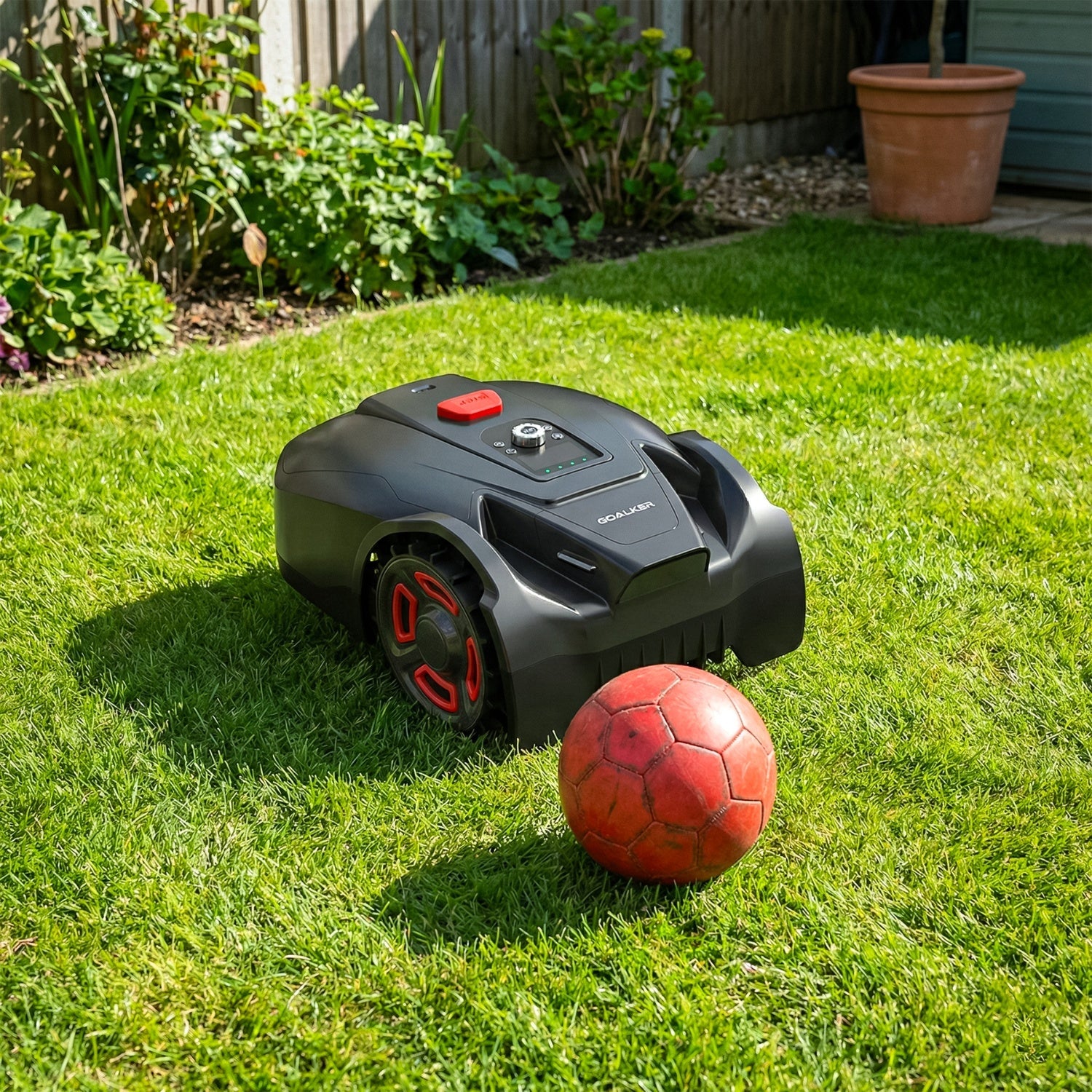 Mähroboter im Garten erkennt Hindernis und stoppt vor einem Fußball auf dem Rasen